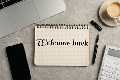 Image of Notebook with phrase Welcome Back on grey table. Office desk with laptop and coffee, flat lay