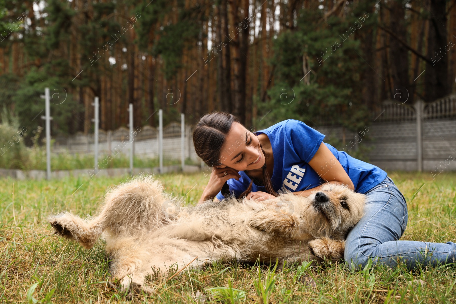 Photo of Female volunteer with homeless dog at animal shelter outdoors