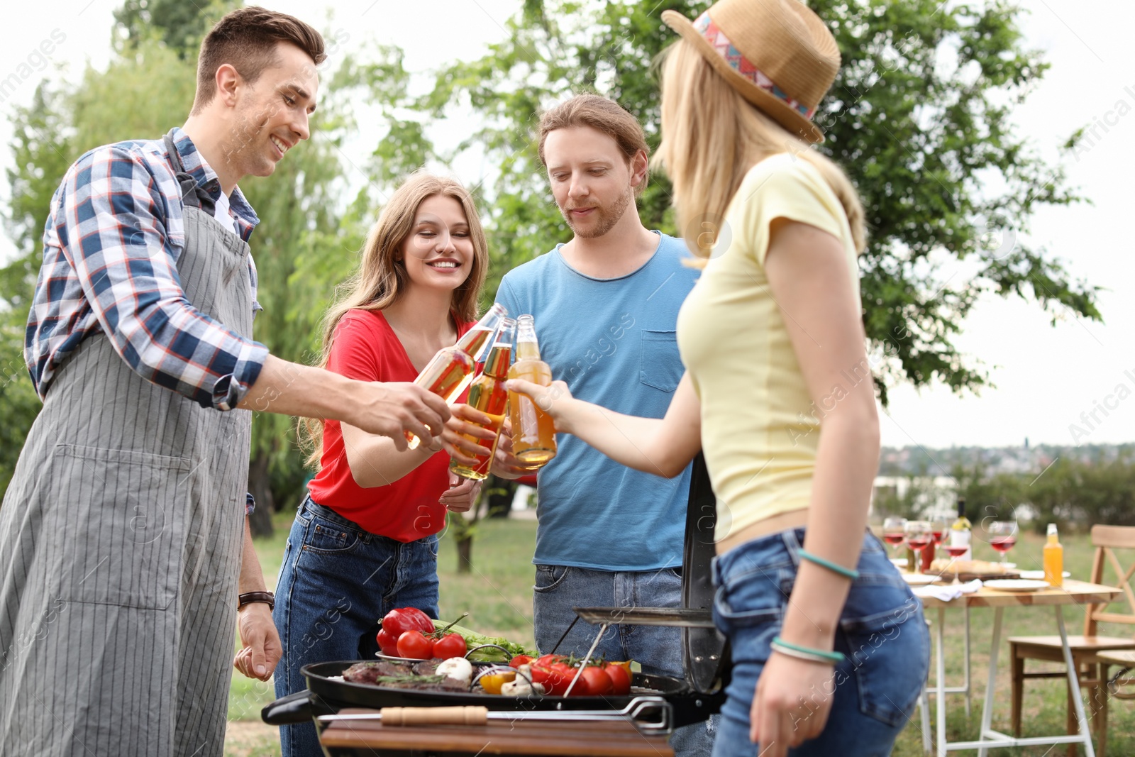 Photo of Young people having barbecue with modern grill outdoors