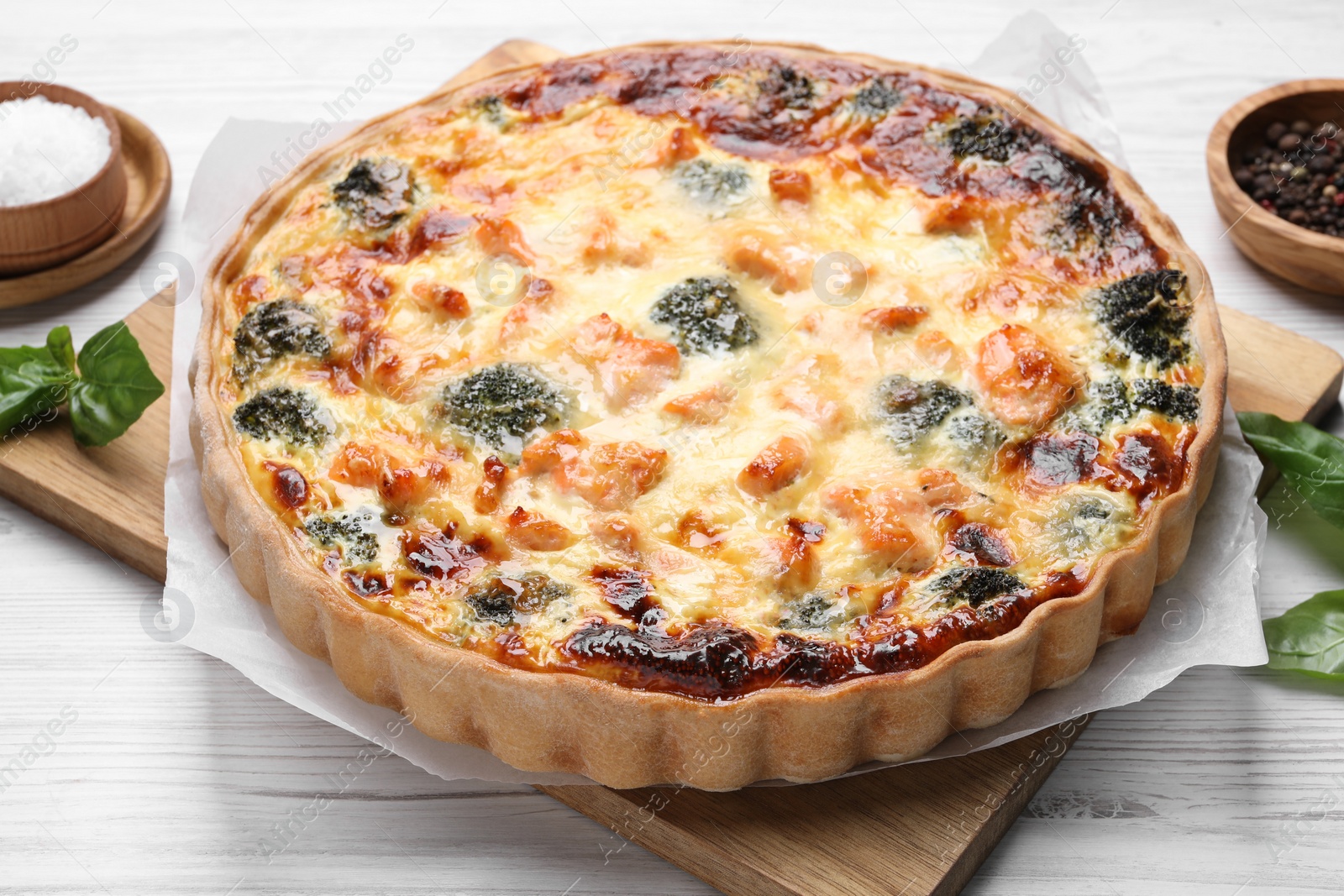 Photo of Delicious homemade quiche with salmon and broccoli on white wooden table