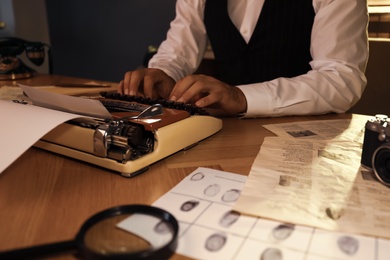 Photo of Old fashioned detective working with typewriter at table in office, closeup