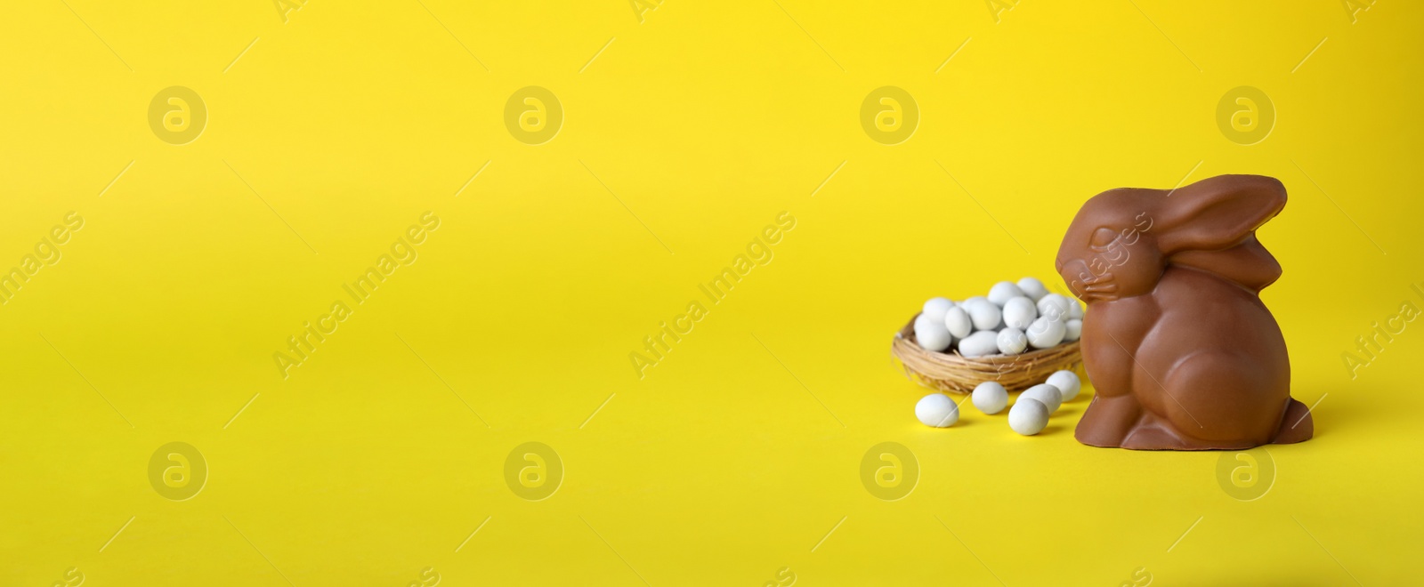 Photo of Chocolate Easter bunny and candies on yellow background