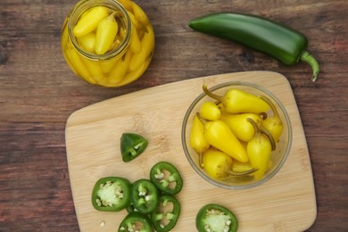 Fresh and pickled jalapeno peppers on wooden table, flat lay