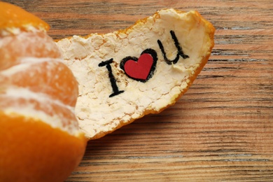 Tangerine peel with phrase I Love You on wooden background, closeup