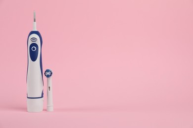 Photo of Electric toothbrush on pink background, space for text
