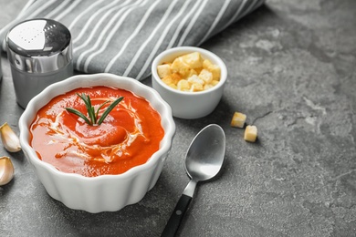 Photo of Fresh homemade tomato soup served with croutons on grey table. Space for text