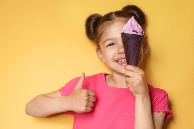 Photo of Adorable little girl with delicious ice cream against color background