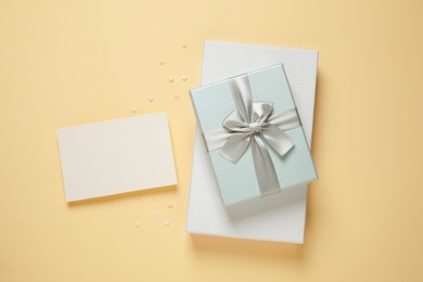 Photo of Beautiful gift boxes and blank card on beige background, flat lay. Space for text