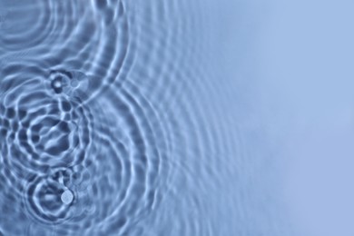 Closeup view of water with circles on blue background. Space for text