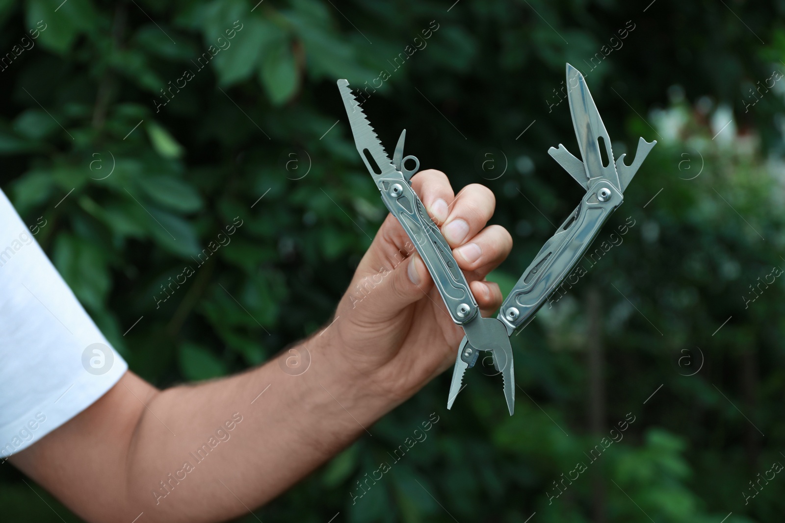 Photo of Man holding compact portable multitool outdoors, closeup