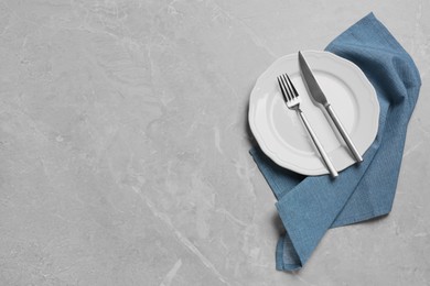 Clean plate with shiny silver cutlery on grey marble table, flat lay. Space for text