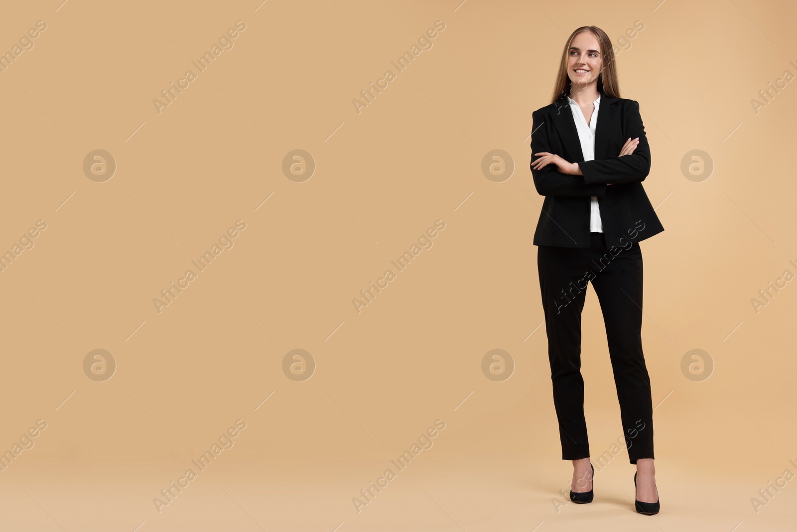 Photo of Happy young secretary with crossed arms on beige background, space for text