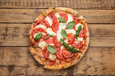 Photo of Delicious Caprese pizza with tomatoes, mozzarella and basil on wooden table, top view