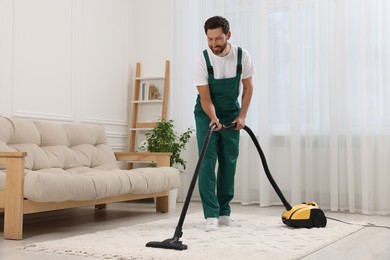 Photo of Dry cleaner's employee hoovering carpet with vacuum cleaner in room