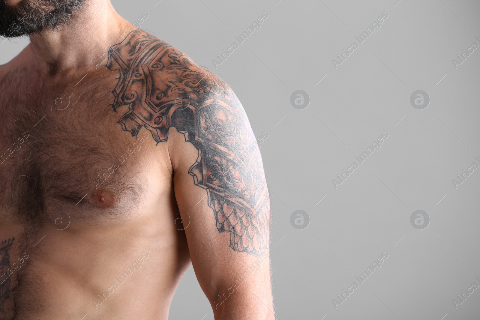 Photo of Tattooed man on grey background, closeup view. Space for text