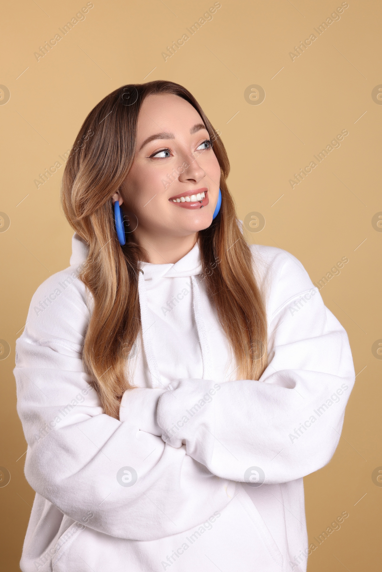 Photo of Young woman with lip piercing on beige background