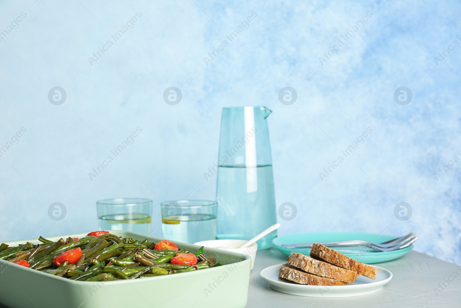 Photo of Dish with tasty green beans and tomatoes on table