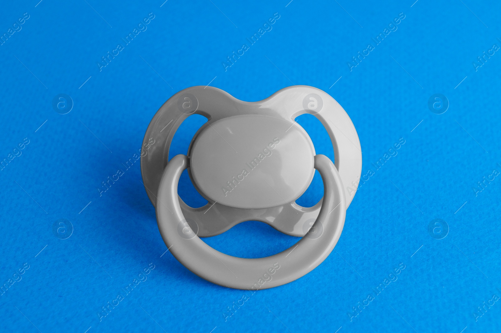 Photo of One new baby pacifier on blue background