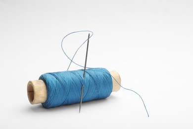 Photo of Light blue sewing thread with needle on white background