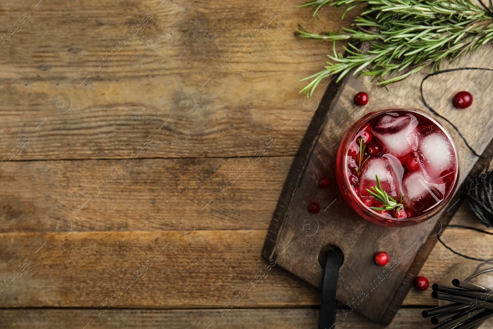 Photo of Tasty refreshing cranberry cocktail with rosemary on wooden table, flat lay. Space for text