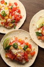 Photo of Delicious tacos with vegetables and lime on wooden table, top view