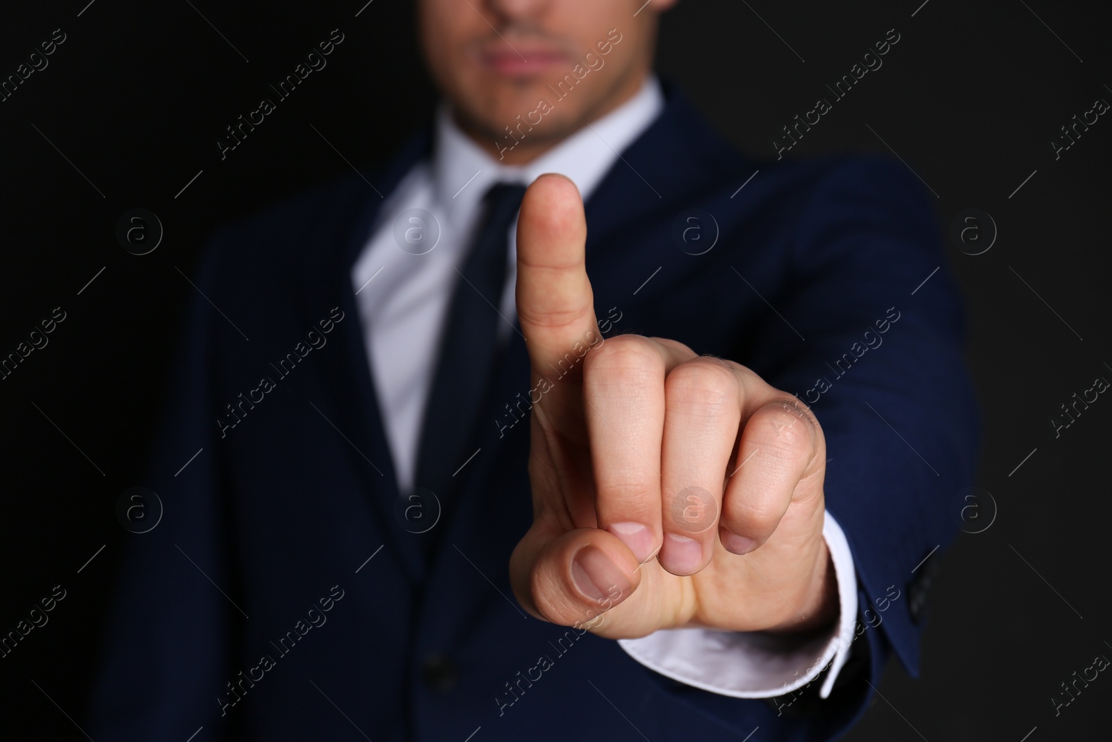 Photo of Businessman pointing at something on black background, closeup. Finger gesture