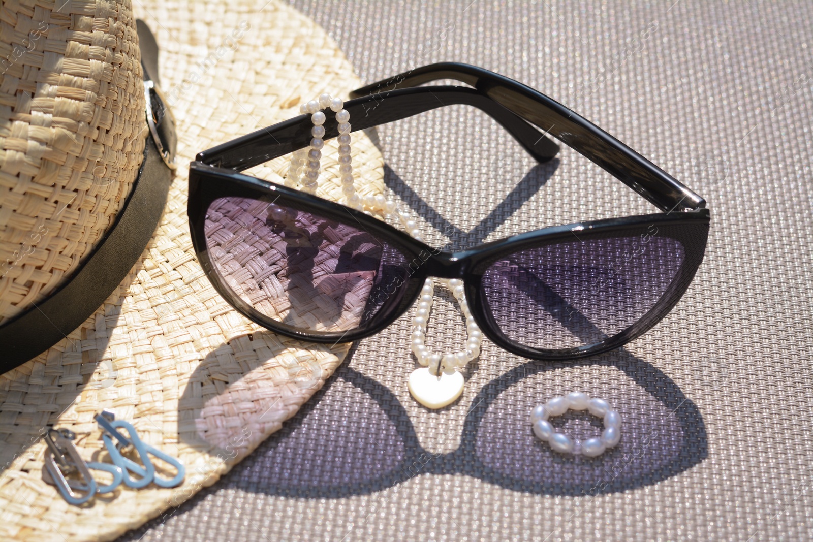 Photo of Stylish hat, sunglasses and jewelry on grey surface, closeup