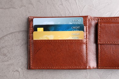 Photo of Credit cards in leather wallet on grey textured table, top view