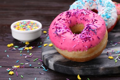 Sweet glazed donuts decorated with sprinkles on wooden table, space for text. Tasty confectionery