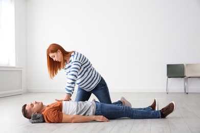 Woman practicing first aid on unconscious man indoors