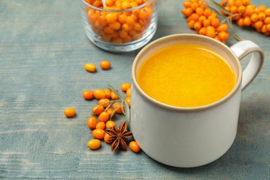 Photo of Fresh sea buckthorn tea on blue wooden table