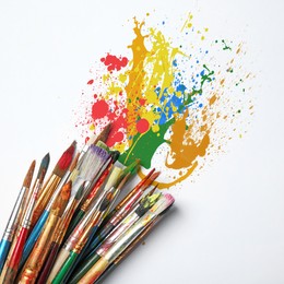 Image of Different brushes and paint splatters on white background, top view