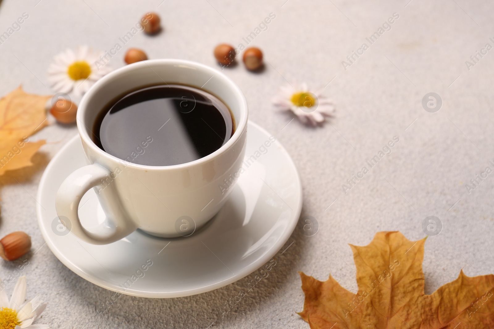 Photo of Composition with cup of hot drink and autumn leaves on light grey textured table, closeup