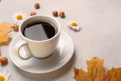 Composition with cup of hot drink and autumn leaves on light grey textured table, closeup