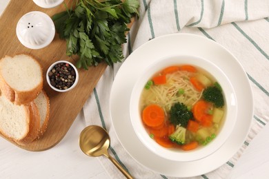 Photo of Delicious vegetable soup with noodles served on white wooden table, flat lay