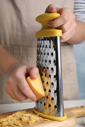 Photo of Woman grating fresh cheese at table, closeup