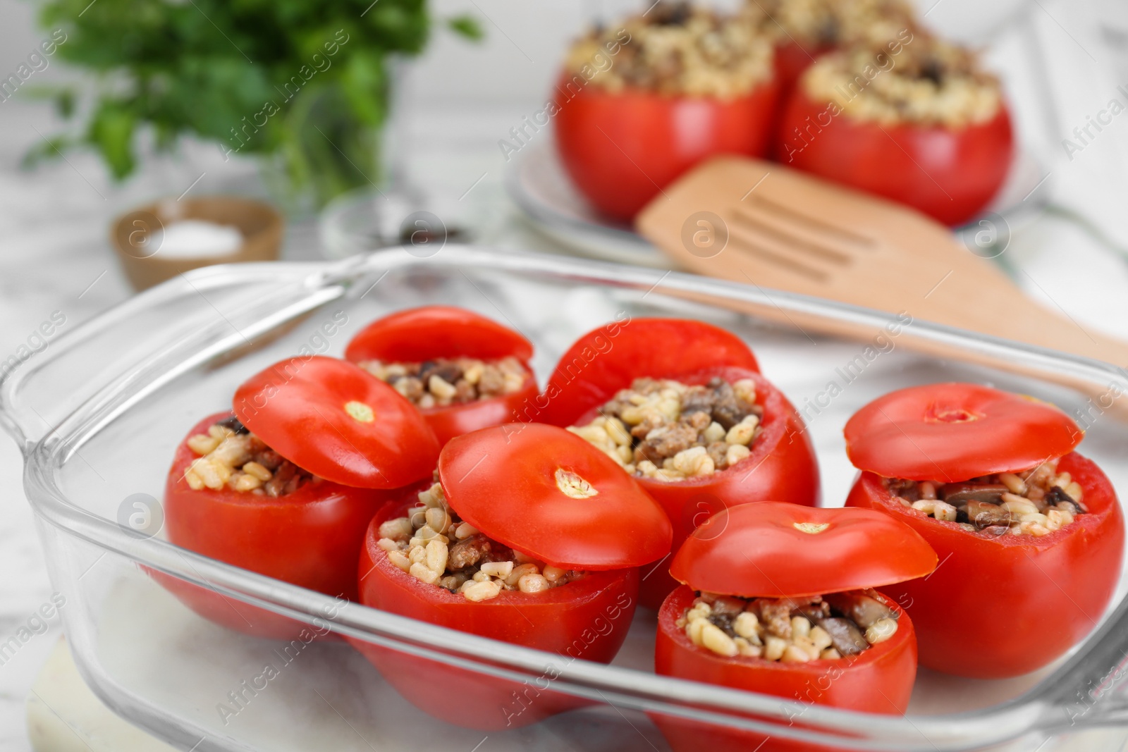 Photo of Delicious stuffed tomatoes with minced beef, bulgur and mushrooms in glass baking dish, closeup