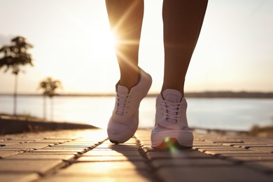 Young woman running near river in morning, closeup