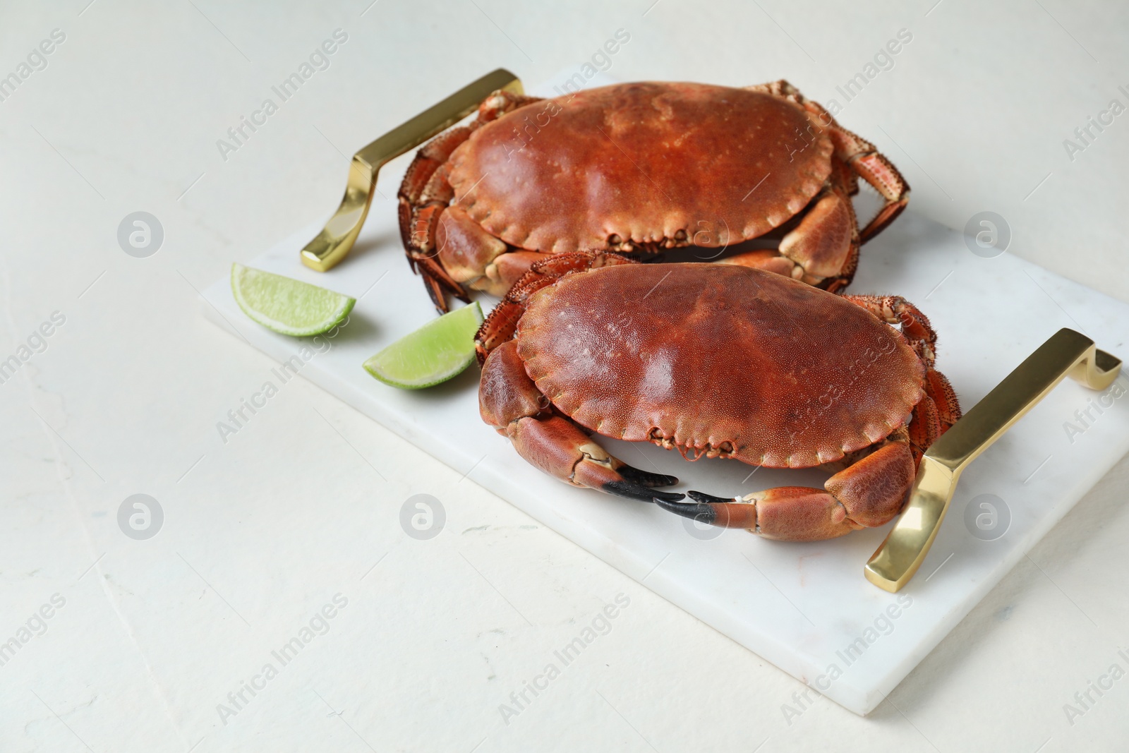 Photo of Delicious boiled crabs and lime on white table. Space for text