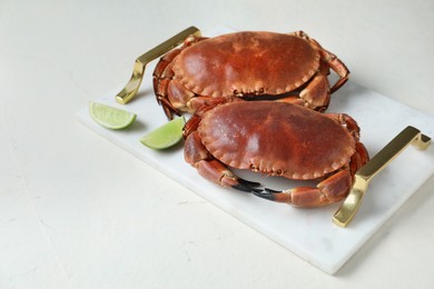 Photo of Delicious boiled crabs and lime on white table. Space for text