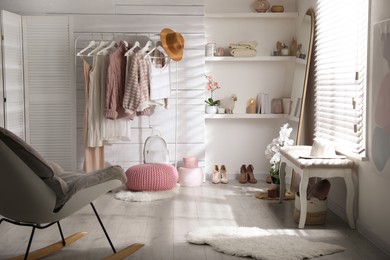 Photo of Rack with different stylish clothes, shoes and decorative elements in dressing room. Interior design