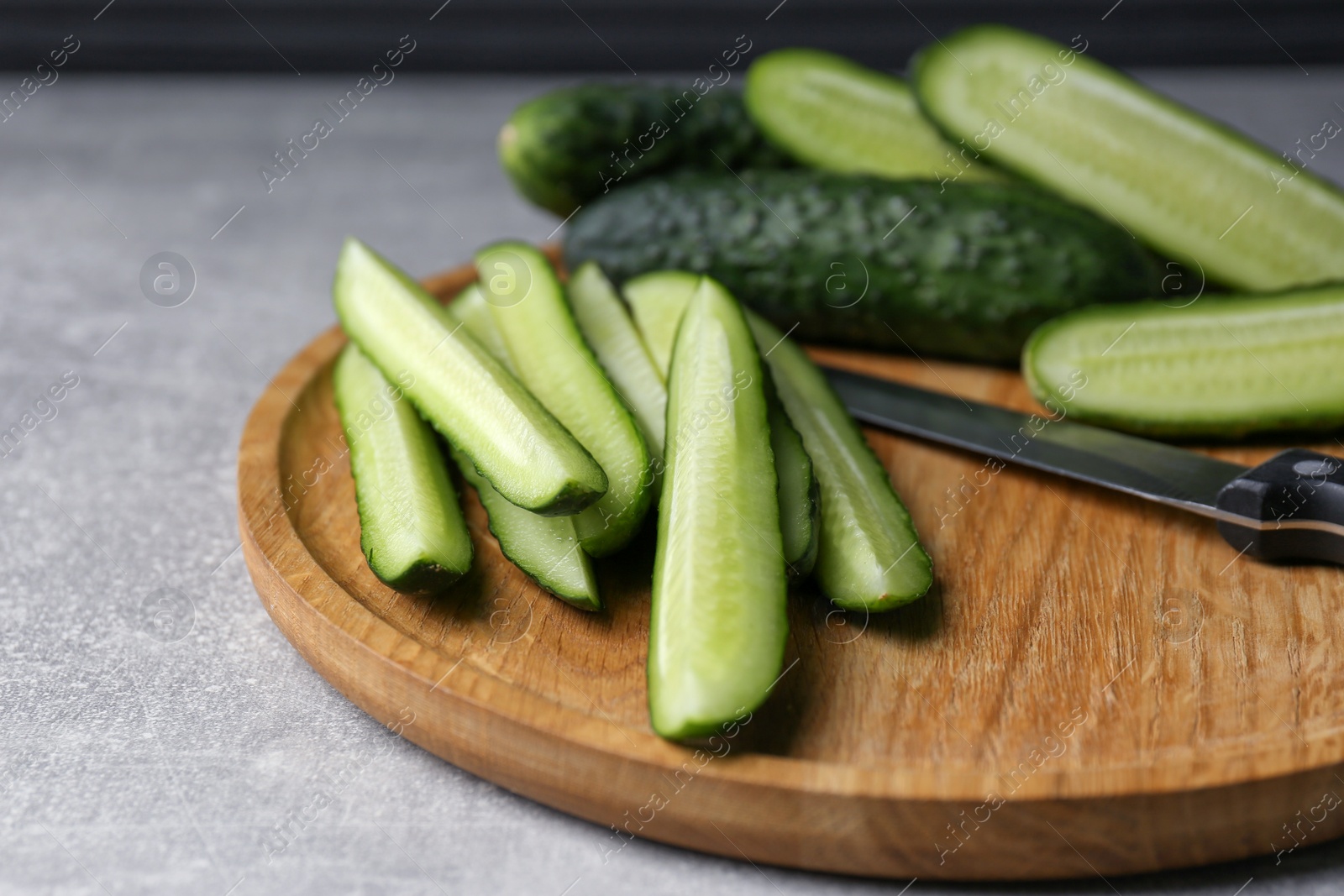 Photo of Whole and cut fresh ripe cucumbers on grey table