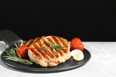 Delicious grilled pork steaks with spices on gray table against black background, space for text