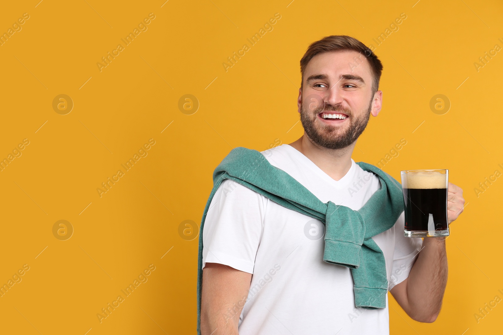 Photo of Handsome man with cold kvass on yellow background. Traditional Russian summer drink