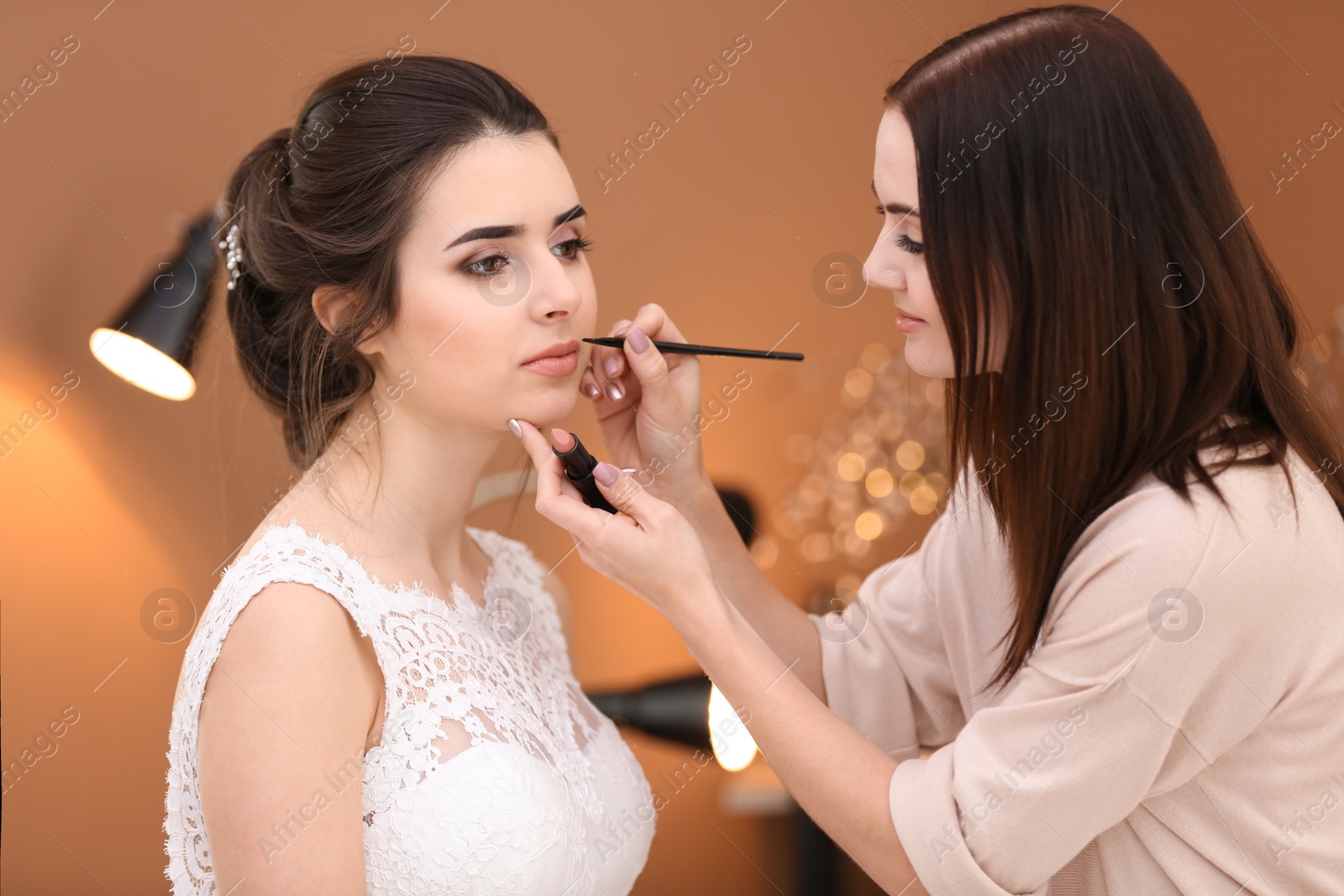 Photo of Professional makeup artist working with young bride in salon