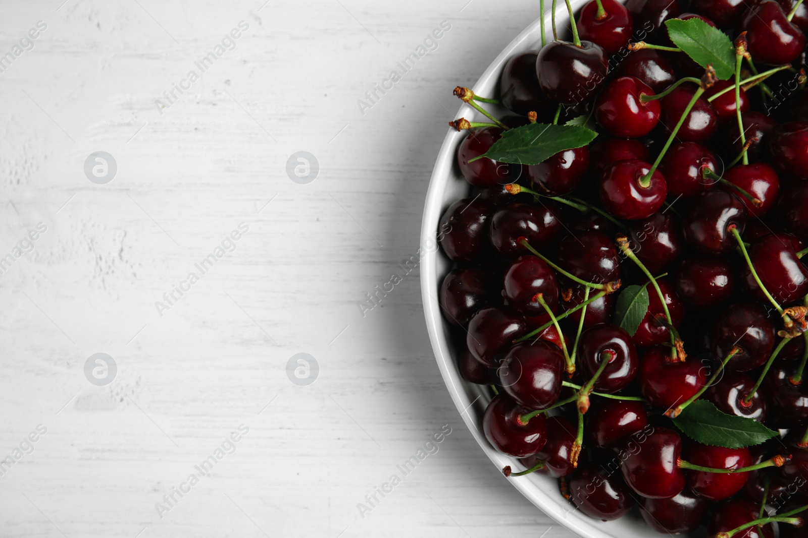 Photo of Plate with sweet red cherries on wooden table, top view