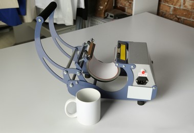 Photo of Printing logo. Heat press and cup on white table
