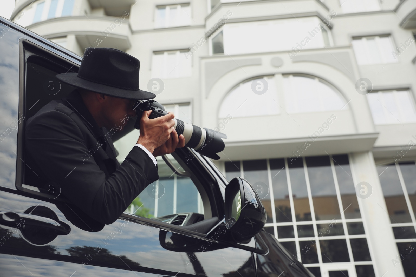 Photo of Private detective with camera spying from car