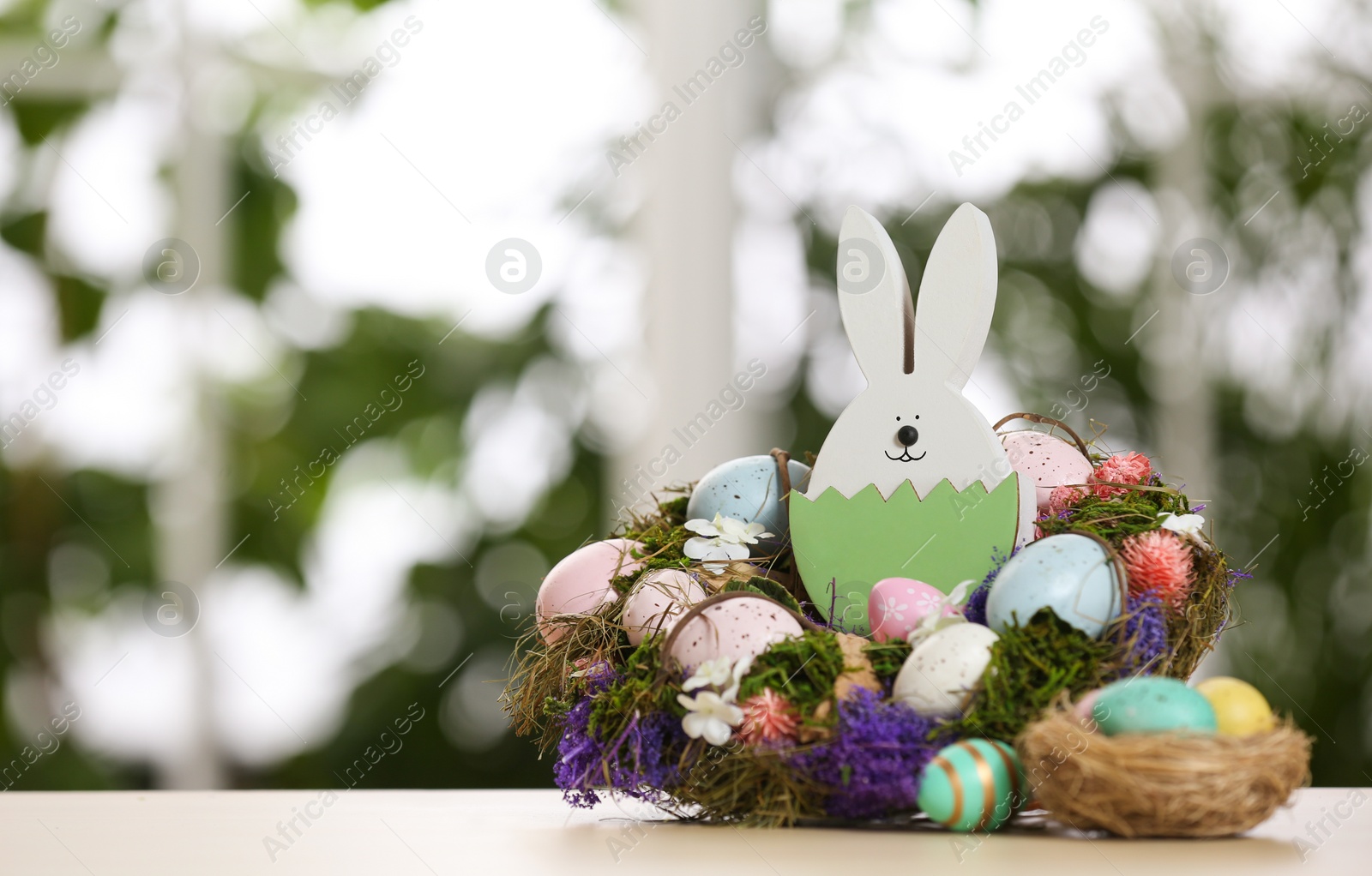 Photo of Festive composition with Easter eggs on table against blurred window, space for text