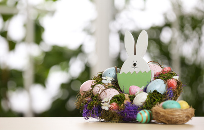 Festive composition with Easter eggs on table against blurred window, space for text